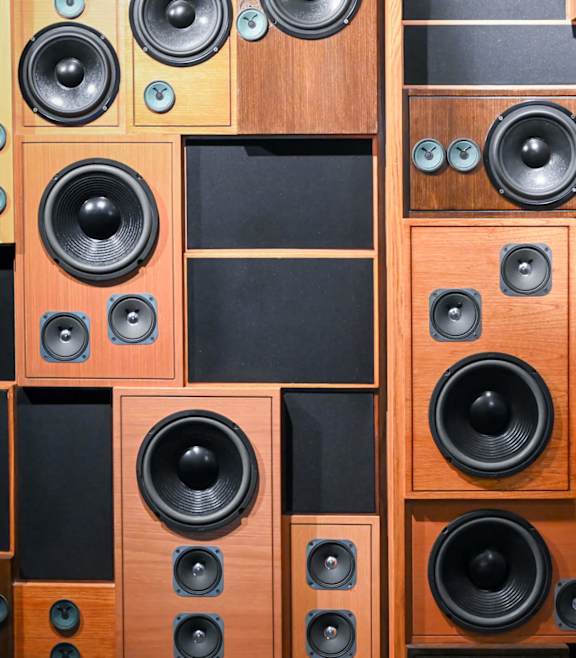 A wall of speakers with black cones and wooden cabinets.