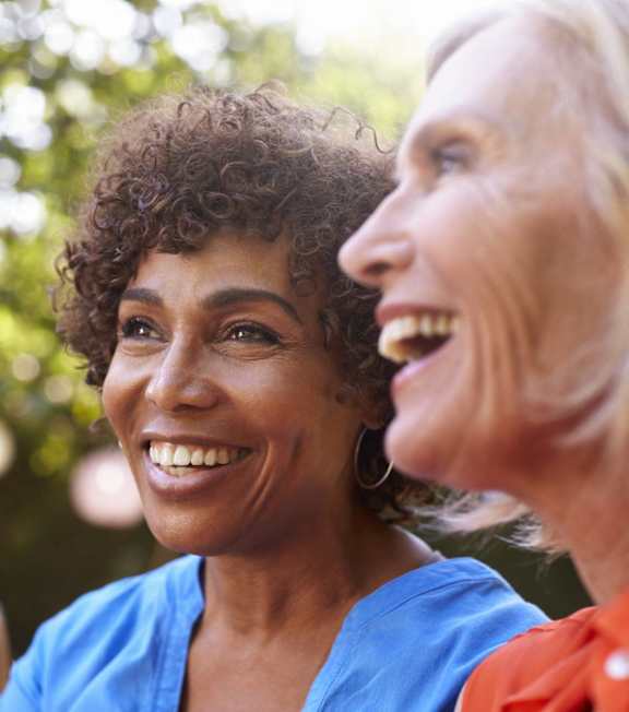 Three women are laughing together in a park.