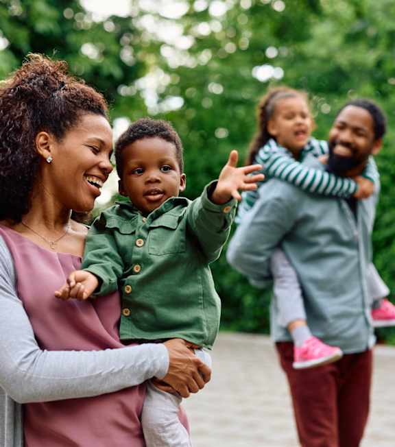 A woman is holding a child while two other children are being carried by adults.