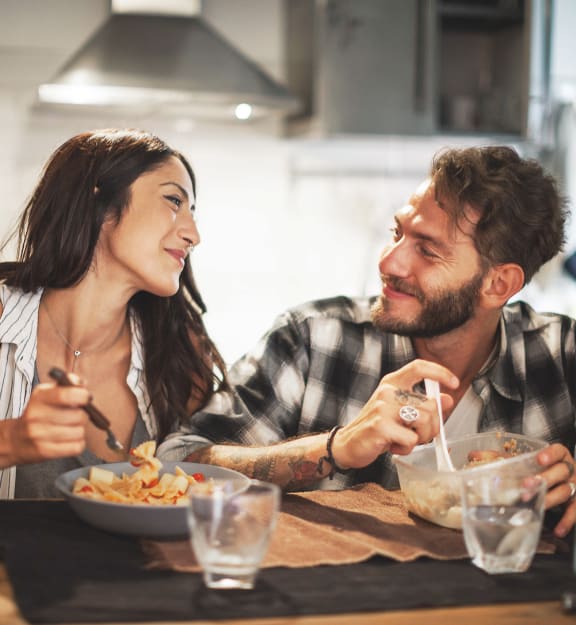 a man and a woman sitting at a table eating a bowl of food