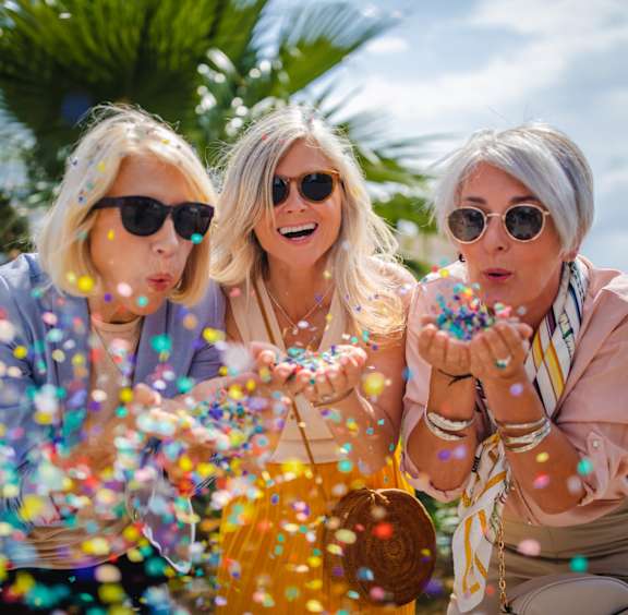 Three women blowing bubbles in the air.
