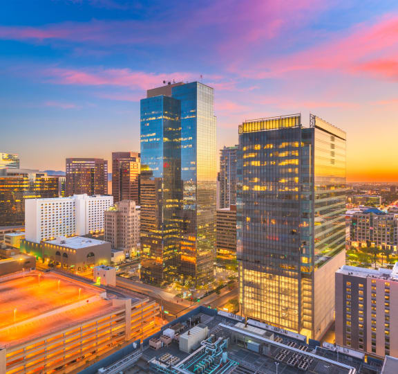 A cityscape at sunset with a variety of buildings and a sports arena at The Rey Downtown, Phoenix, 85003