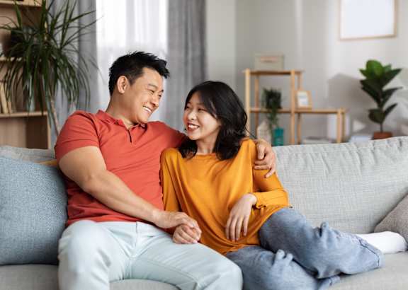A man and woman are standing in a kitchen, sharing a moment together.