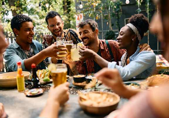 A group of people toasting with beer glasses at a table at Apex, Colorado Springs, 80923