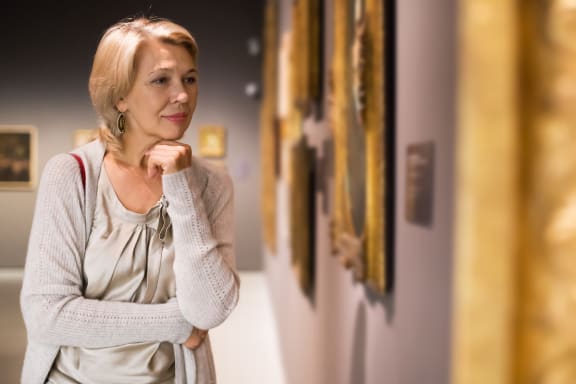 a woman looks at paintings in an art gallery
