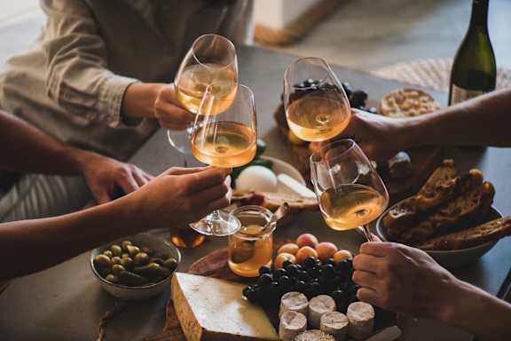A group of people toasting with wine glasses at a table full of food at Apex, Colorado Springs