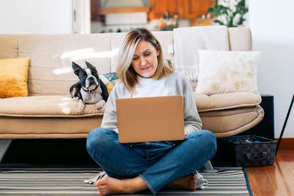 A woman sitting on the floor with a laptop in front of a couch with a dog on the couch at Apex, Colorado Springs, CO, Colorado