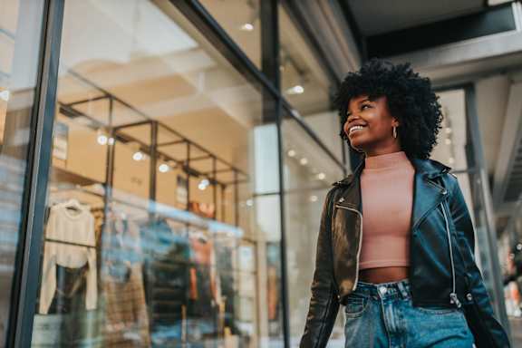 A woman with an afro hairstyle is standing outside a clothing store. at The Woodlands Apartments, Milton Keynes