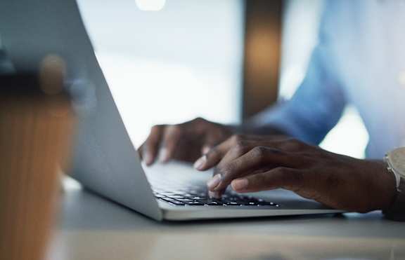 A person is typing on a laptop with a smartphone and a watch on the side. at Berewick Pointe Apartments , Charlotte, NC