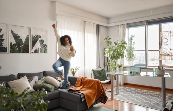 a woman jumping on a couch in a living room