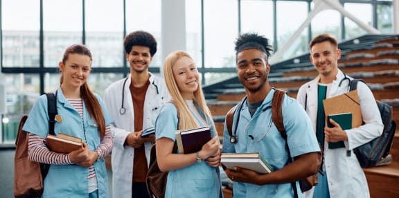 a group of healthcare professionals standing in a lobby with notebooks and books