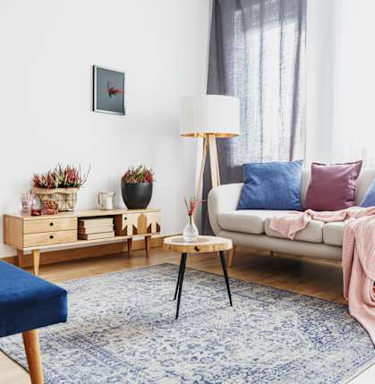 A living room with a blue rug and a white couch.