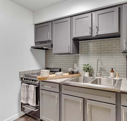 a kitchen with gray cabinets and white counter tops and a sink