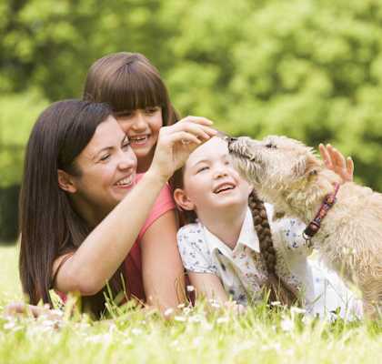 a woman and two children playing with a dog
