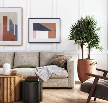 A living room with a couch, a chair, a table, and two framed pictures on the wall.