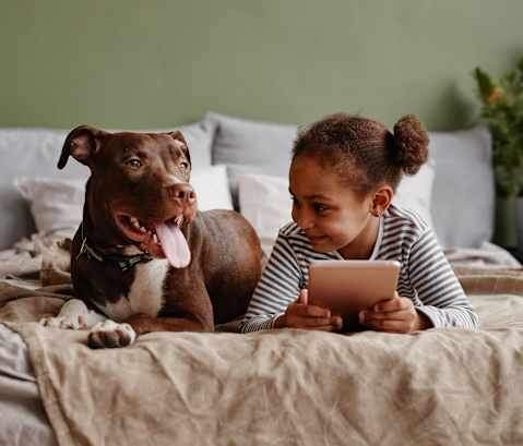 a girl and her dog laying on a bed looking at a tablet at North Grove, Riverside