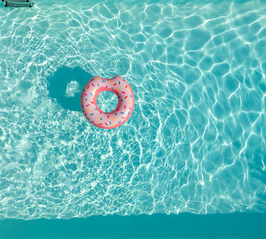 A pink donut float in a blue swimming pool.