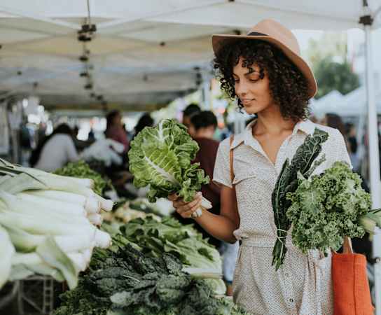 a woman holding a bunch of cabbages at a farmers market at The Canyons at Linda Vista Trail, Oro Valley, AZ, 85704