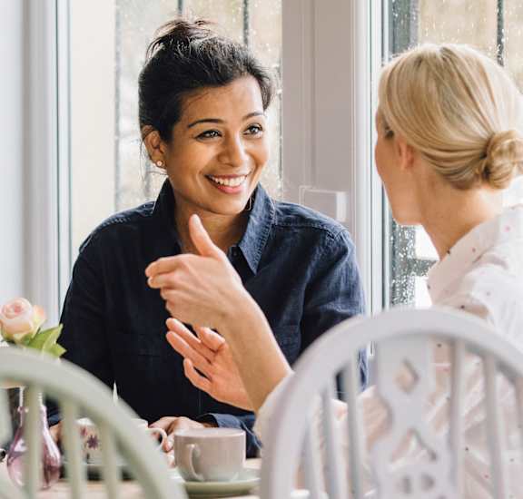 two women sitting at a table talking to each other at Randolph Park, Charlotte, 28211