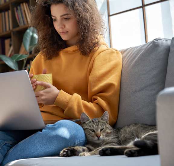 a woman sitting on a couch with a cat and a laptopat Randolph Park, Charlotte North Carolina