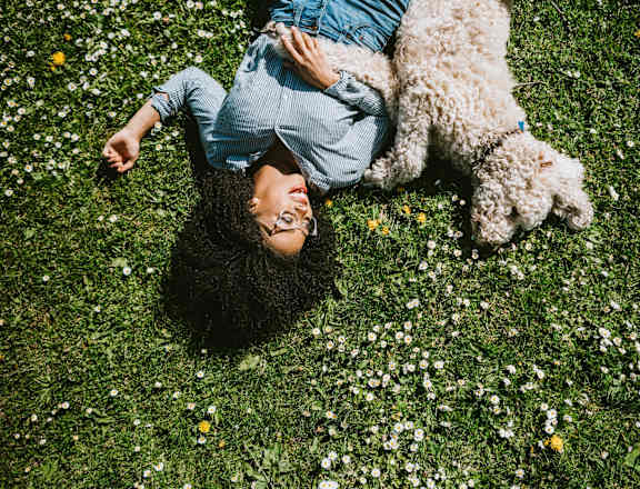 a woman laying in the grass with a dog