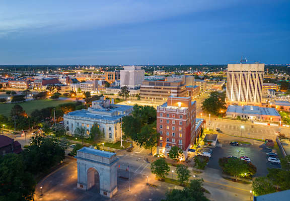 A cityscape at dusk with a prominent archway in the foreground.