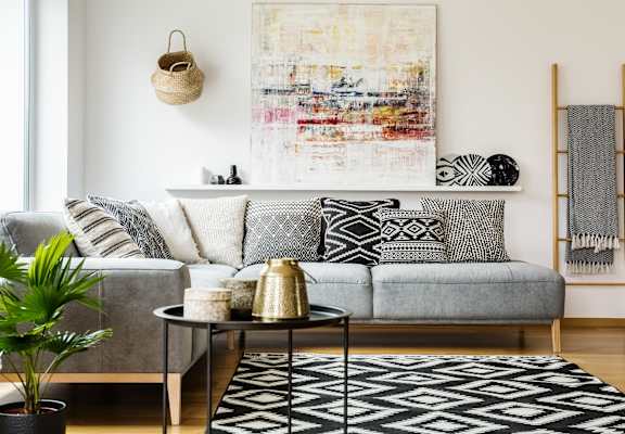 a living room with a gray couch and a black and white rug