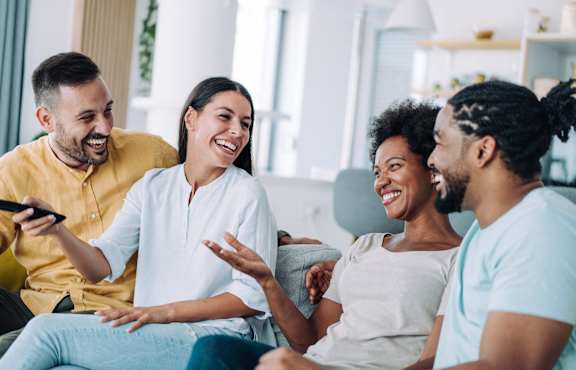 a group of people sitting on a couch laughing and talking