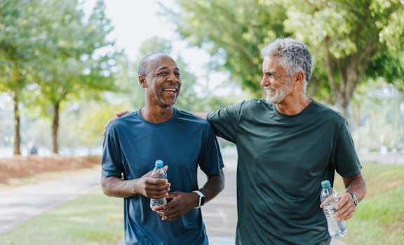 Two men are walking and talking in a park.