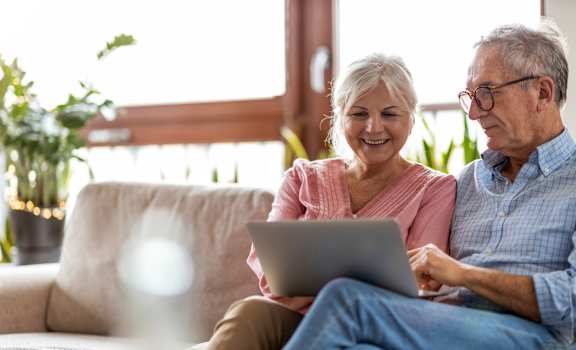 a man and woman sitting on a couch with a laptop at Village Oaks Apartments, Austin, Texas