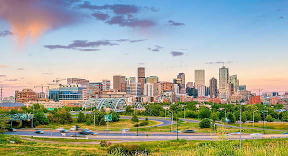A city skyline at sunset with a bridge in the foreground.