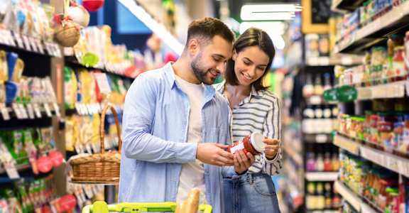 a man and a woman in a grocery store looking at a product