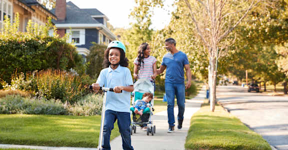 A family of four is riding a scooter down a suburban street at Walker Place Apartments, Texas, 76643