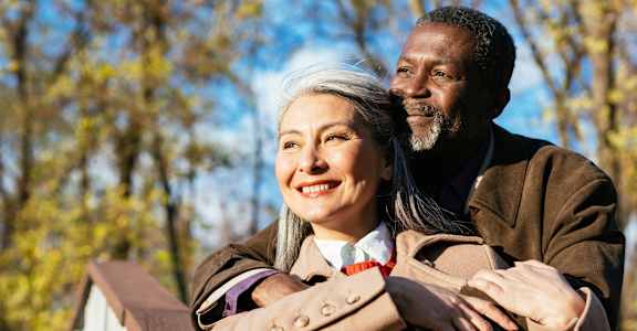 A man and a woman are standing close together on a bridge.