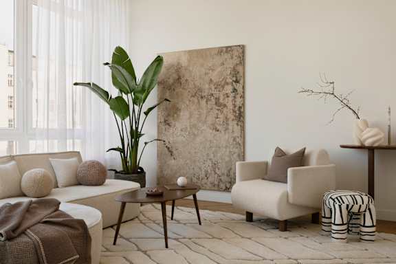 A living room with a large painting on the wall and a plant in a pot.