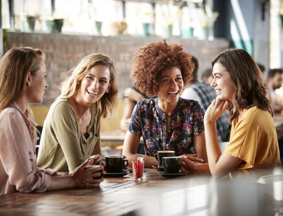 a group of women sitting at a table drinking coffee