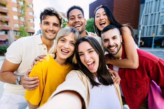 a group of people posing for a picture with a cell phone
