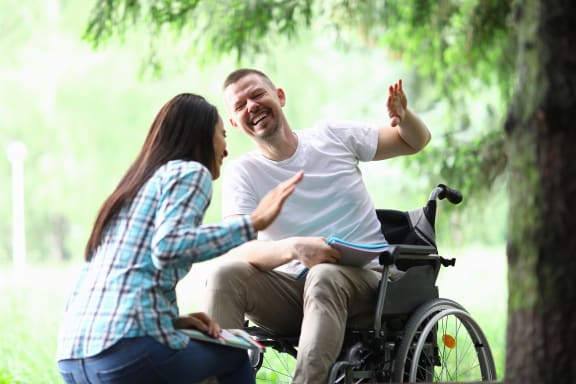 a man in a wheelchair talks to a woman in a park