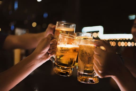 people holding up glasses of beer at a bar
