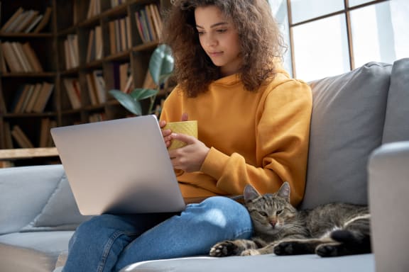 a woman sitting on a couch with a cat and a laptop at 2300 West Apartments, Nevada, 89502
