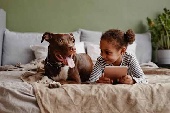 A girl is lying on a bed with a brown dog. at North Grove Apartments, California, 92501