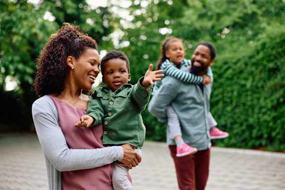 A woman is holding a child while two other children are being carried by adults.