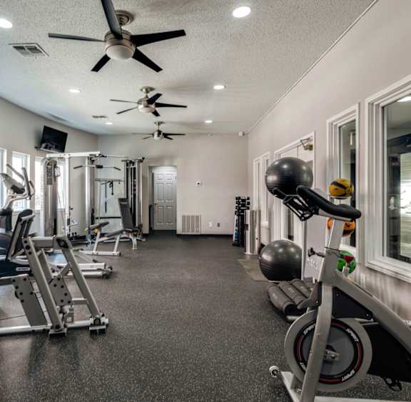 A spacious gym with a variety of equipment including treadmills, stationary bikes, and weight machines.
