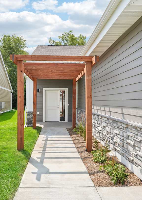 A wooden pergola is attached to a house.