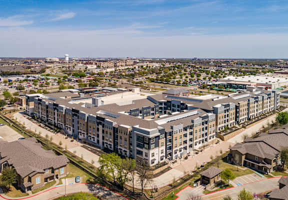 A large apartment complex is surrounded by smaller buildings and houses.