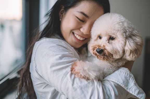 a woman is holding a small white dog