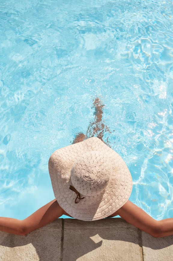 a woman in a floppy hat laying in a pool