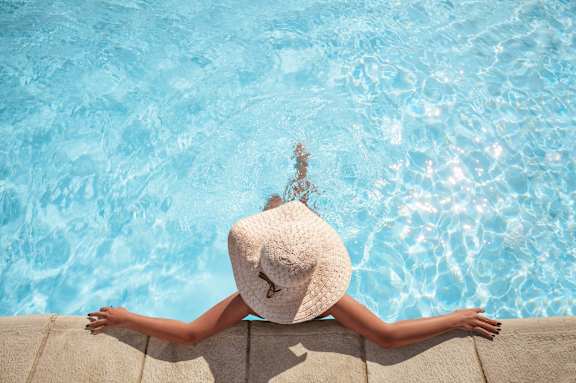 a woman in a floppy hat laying in a pool