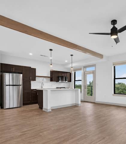 A spacious room with a ceiling fan and a large window overlooking greenery.