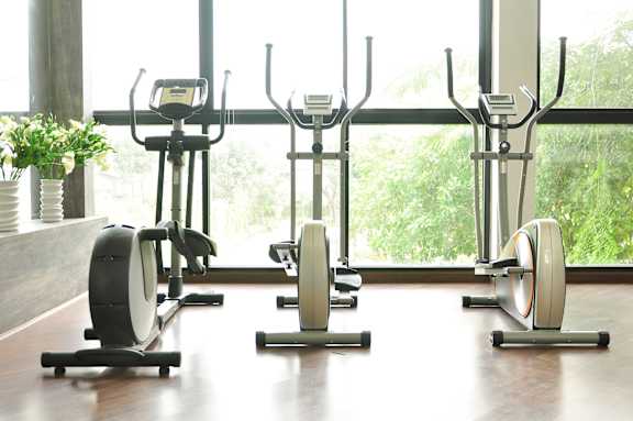 A row of stationary bikes are lined up in a row in a gym.
